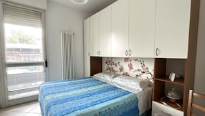 A bedroom with a bed, a radiator, a window with blinds, and a wardrobe. - SE131 - Senigallia, two-room apartment with air conditioning and terrace (Senigallia)