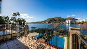 Une terrasse avec une piscine, des palmiers et une vue sur un lac et des montagnes.