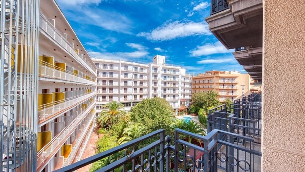 Ein mehrstöckiges Hotel mit Balkonen, einem Schwimmbad und üppigem Grün.