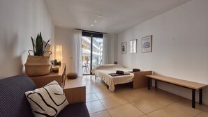Ein modernes Hotelzimmer mit Bett, Sitzbank, Sofa, Topfpflanze und Kunstwerken an den Wänden.