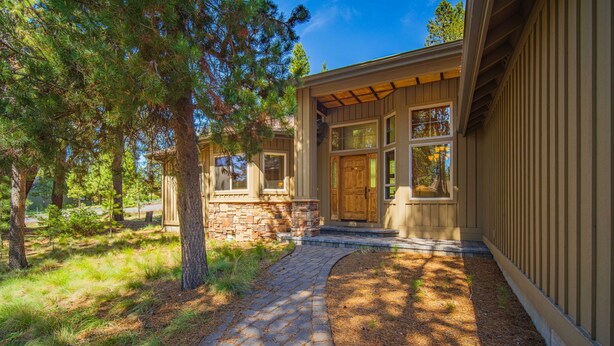 Une maison avec des fondations en pierre, une porte d’entrée en bois et un chemin en briques menant à l’entrée.