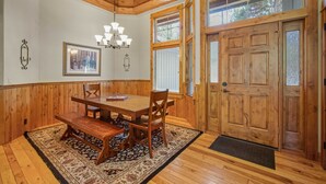 Un coin repas avec une table et des chaises en bois, un lustre et une grande porte en bois dotée de panneaux de verre.