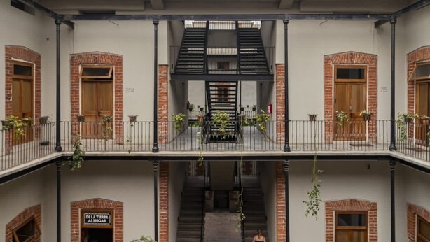 A multi-level courtyard with brick walls, wooden doors, and metal railings. - Departamento Emilio Dondé zona céntrica CDMX (Ciudad de México)