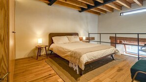 A bedroom with a wooden ceiling, a bed with a headboard, a nightstand with a lamp, and a view of the outside balcony. - Departamento Emilio Dondé zona céntrica CDMX (Ciudad de México)