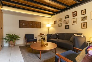 A living room with a sofa, armchairs, a coffee table, a lamp, and framed pictures on the wall.