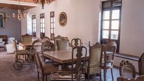 Un espace repas avec une grande table en bois, des chaises en osier et un lustre.