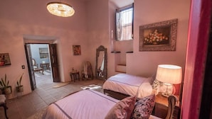 Une chambre avec deux lits, un lustre, un miroir et une fenêtre.