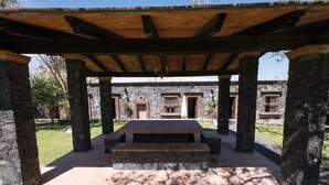 Un espace extérieur abrité, doté de piliers en pierre et d’une table centrale également en pierre.