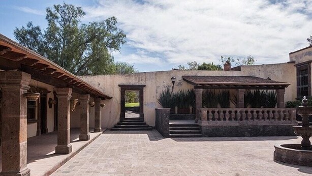 Une cour avec un sol carrelé, des colonnes en pierre et une pergola.