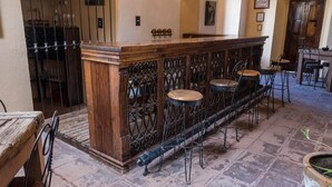 Un espace bar doté d’un comptoir en bois, de trois tabourets et d’une rambarde décorative en métal.