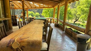 Ein langer Holztisch mit Stühlen, ein Billardtisch und Blick auf eine bewaldete Gegend.