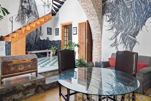 A spacious living area with a glass table, leather chairs, a sofa, and a staircase.