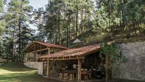 Una cabaña rústica con fachada de madera, un porche cubierto y una pared de piedra.