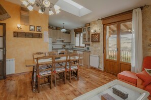 A spacious living area with a dining table and chairs, a sofa, a coffee table, and a view through a large sliding glass door.