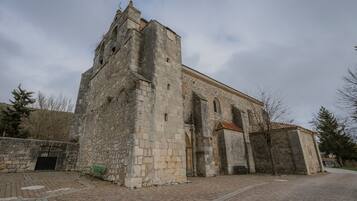 A historic stone building with a tower, a gated entrance, and a paved courtyard.