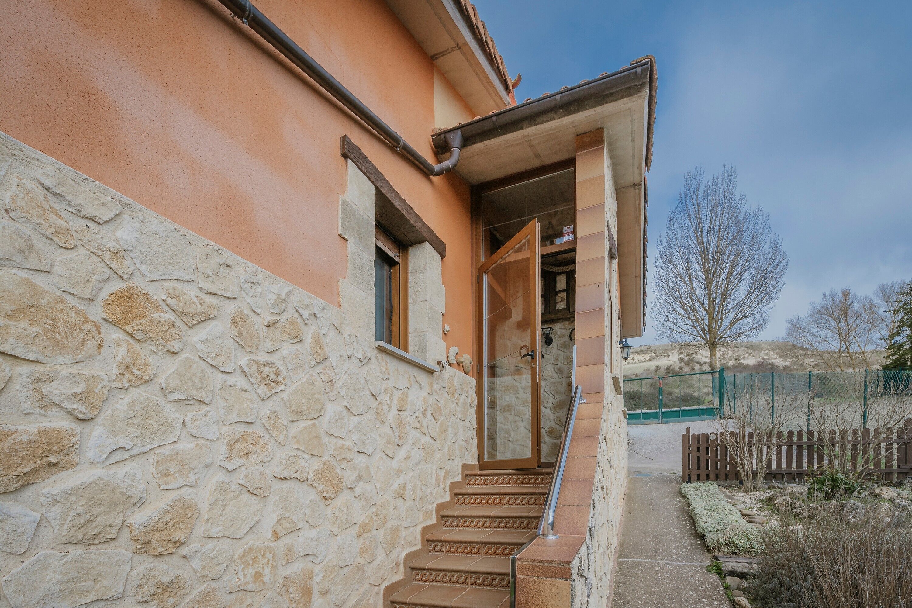 Un mur extérieur en pierre, un escalier et un ciel dégagé.