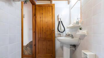 A bathroom with a wooden door, a white sink, and a shower area.