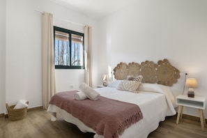 A bedroom with a bed, a bedside table, a lamp, a window with curtains, and a wall-mounted headboard. - Country House 'El Moral' with Mountain View, Private Terrace and Wi-Fi (Prado del Rey)