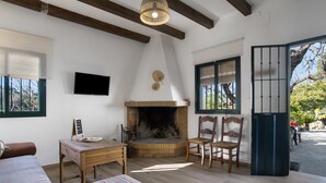 Quarto aconchegante com lareira, televisão, mesa de jantar e uma janela grande.