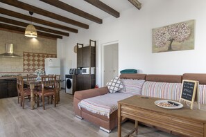 A modern kitchen with a dining area, a sofa, and a table with a plate of food. - Country House 'El Moral' with Mountain View, Private Terrace and Wi-Fi (Prado del Rey)