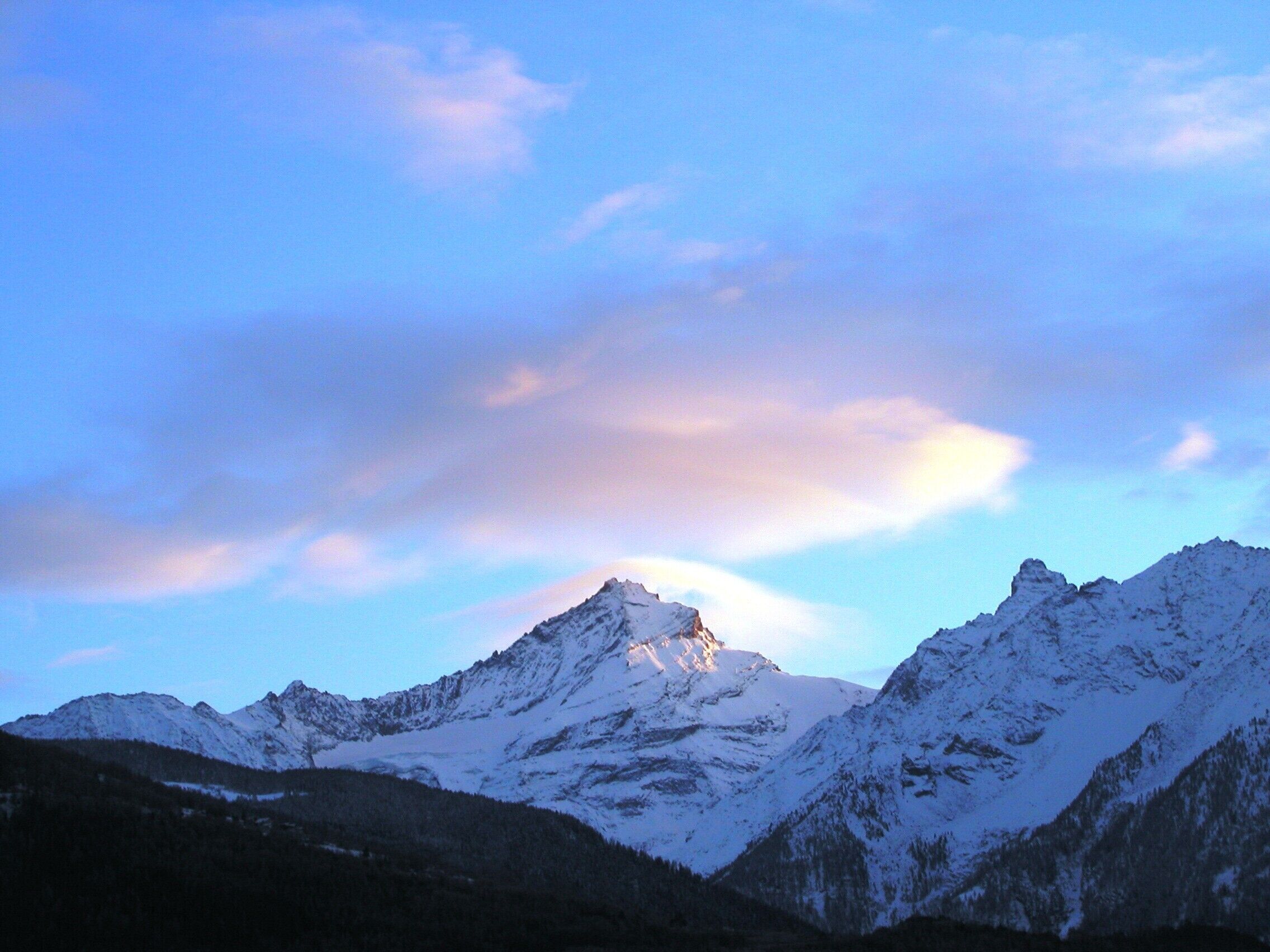 Une chaîne de montagnes aux sommets enneigés, sous un ciel dégagé.