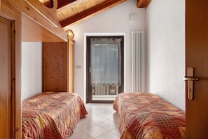 A room with two beds, wooden ceiling beams, a window with a curtain, and a door. - Apartment 'A1' with Mountain View, Shared Garden and Wi-Fi (Saint Pierre)
