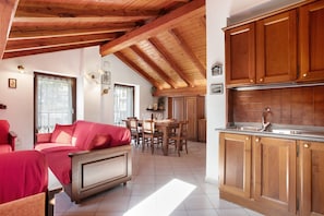 Una stanza con un letto, un tavolo da pranzo con sedie, armadietti in legno e un angolo cottura con lavello.