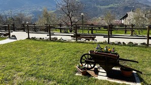 Un parc avec une clôture en bois, un banc et une brouette remplie de fleurs.