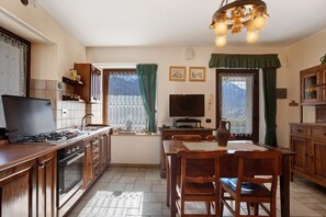 Een keuken met een gasfornuis, oven en een televisie op een standaard.