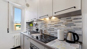 A modern kitchen with a tiled backsplash, stainless steel appliances, and a window providing natural light. - Apartment 'Vista Mare A 150 Mt Dalla Spiaggia' with Sea View, Private Terrace and Air Conditioning (Pietra Ligure)
