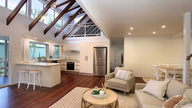 A spacious living area with a kitchen, a dining table, and a sofa. - 6 Dooley Street Bargara (Bargara)