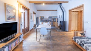 Un salón amplio con una mesa de comedor, sillas, sofá, televisor y una estantería.