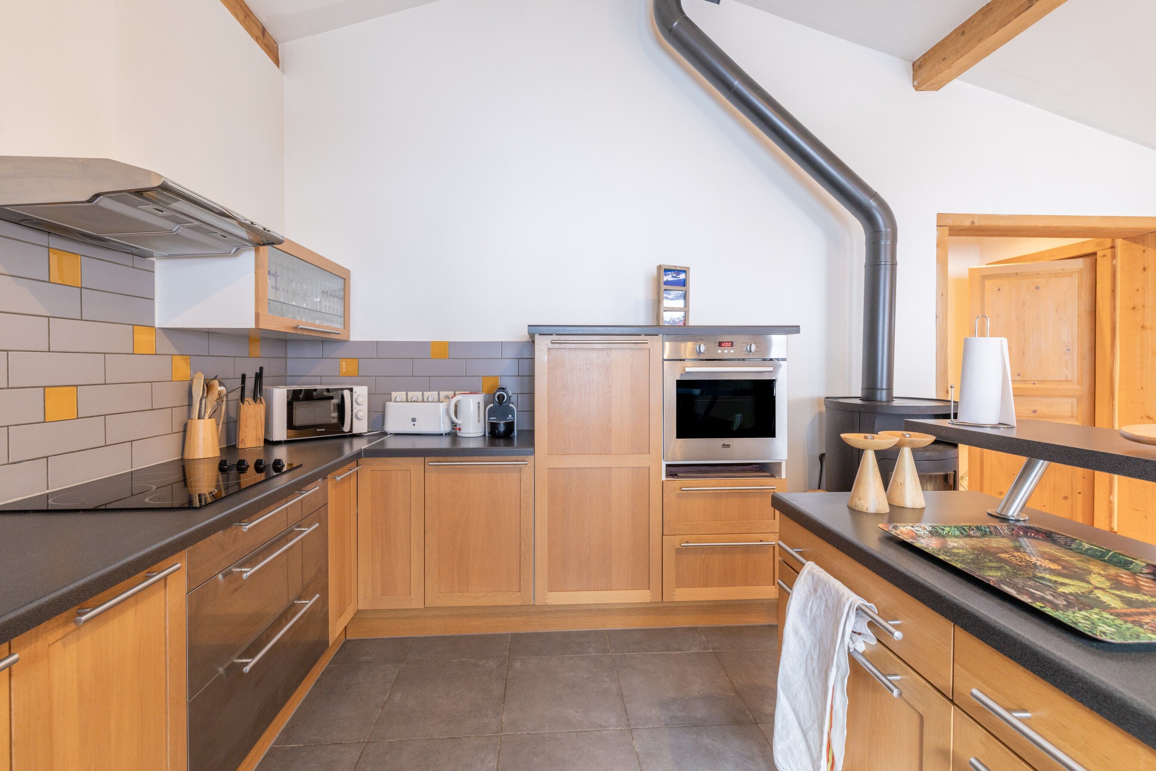 A modern kitchen with wooden cabinets, a built-in microwave, a stove, and a coffee maker.