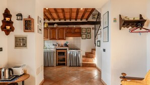 Eine Küche mit Holzausstattung, ein Essbereich mit Tisch und Stühlen sowie eine Treppe zu einer weiteren Ebene.