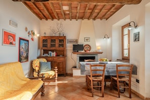A cozy living room with a wooden ceiling, a sofa, a dining table with chairs, a fireplace, and various wall decorations. - Apartment 'Seaview House' with Shared Garden and Wi-Fi (Pietrasanta)