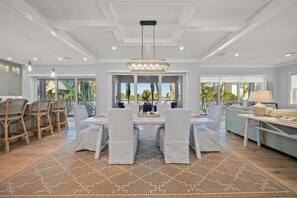 A spacious dining area with a chandelier, dining table, and chairs.