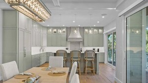 Une cuisine moderne avec des meubles de couleur vert clair, un îlot central et des luminaires suspendus.