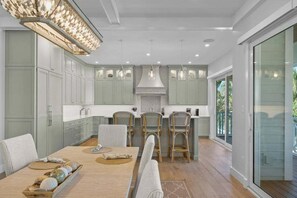 A modern kitchen with light green cabinets, a central island, and pendant lighting.