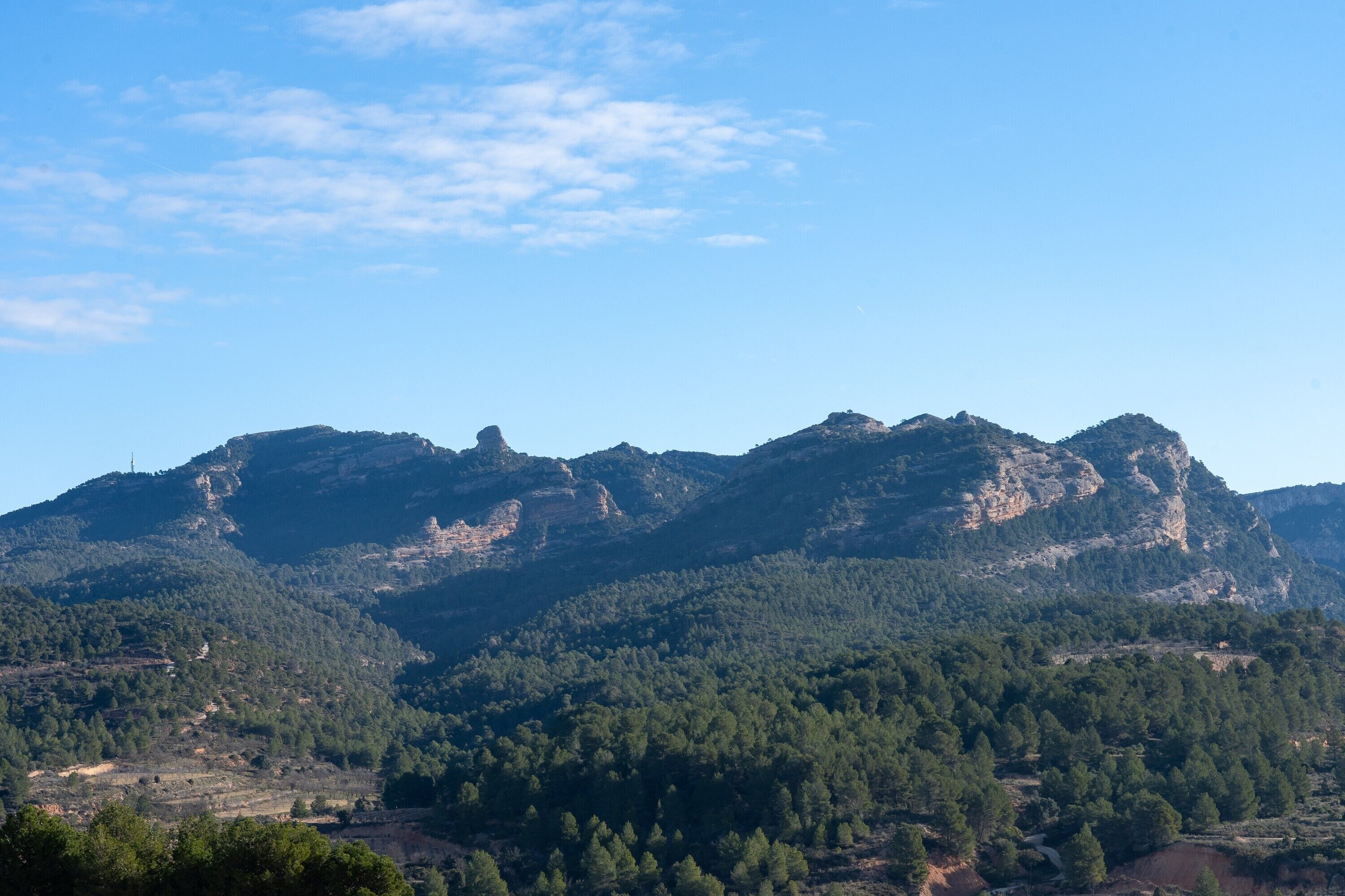 A mountainous landscape with dense forest coverage and rocky outcrops.