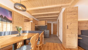 Una cocina moderna con armarios de madera, un comedor con mesa y sillas de madera, y un sofá gris.