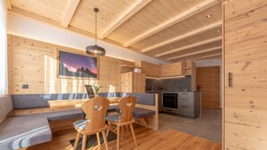 Un interior moderno con paredes de madera, un comedor con mesa y sillas, una cocina y un ventanal con vistas.