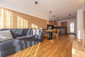 A modern living space with a sofa, a dining table, and a kitchen area.