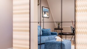A modern living room with a blue sofa, a small table, and a framed picture on the wall. - F27 Living Whg. 08 - F27 Living (Sylt)
