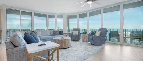A spacious balcony with a view of the ocean, furnished with a sofa, chairs, and a coffee table.