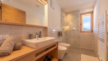 Une salle de bain moderne avec un meuble-lavabo en bois, un grand miroir, une cabine de douche et une vue à travers la porte de la douche.