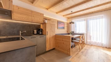Una cucina moderna con mobili in legno, isola integrata e zona pranzo con vista sull'esterno.