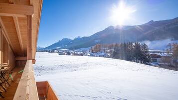 Un bâtiment en bois doté d’un balcon donnant sur un paysage enneigé et des montagnes.