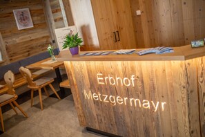 Un comptoir d’accueil avec un revêtement mural en bois et une enseigne indiquant « Erbhof Metzgermayr ».