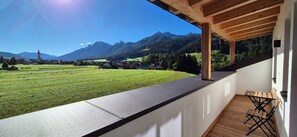 Un balcon donnant sur un paysage montagneux, avec une table en bois et une chaise.