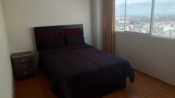Un dormitorio con una cama grande, un aparador y una ventana con vista a la ciudad.